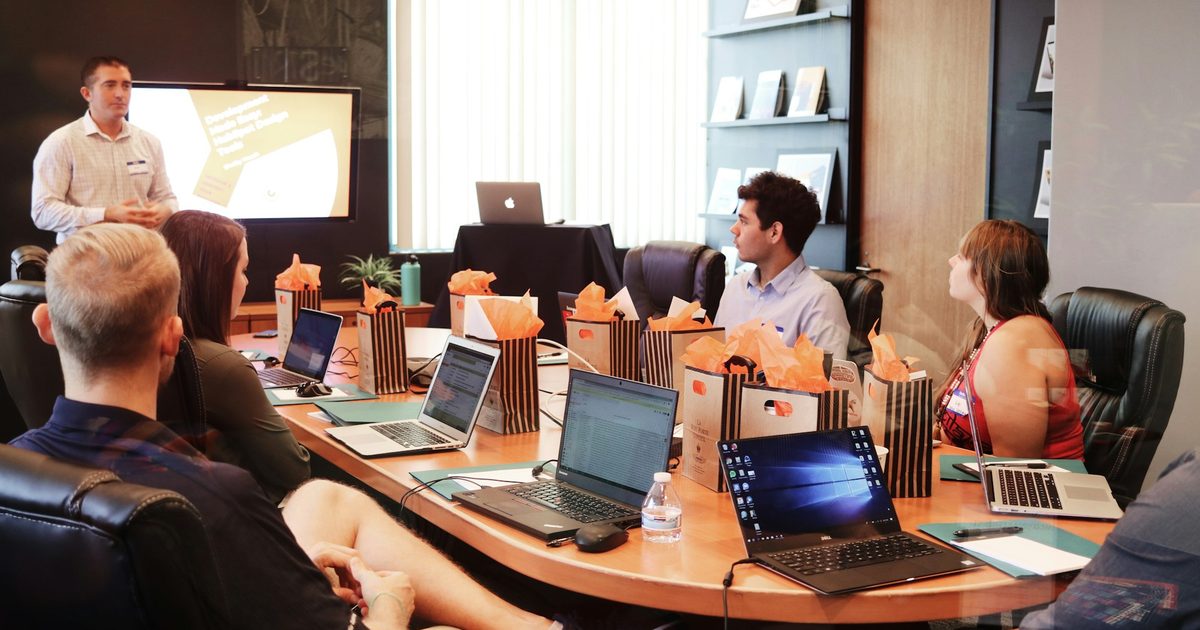 A room of people at laptops during a team presentation
